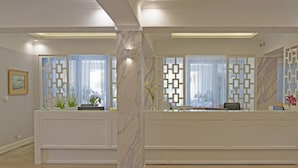 A reception area with a marble column, a reception desk, and a decorative screen. - Alga Baltic Resort (Swinoujscie)