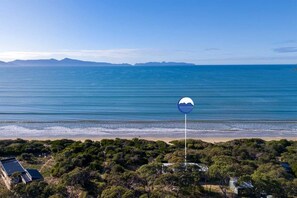 Une propriété située sur la côte, offrant une vue sur la plage, entourée d’une végétation luxuriante et dotée d’un panneau indicateur bien visible.