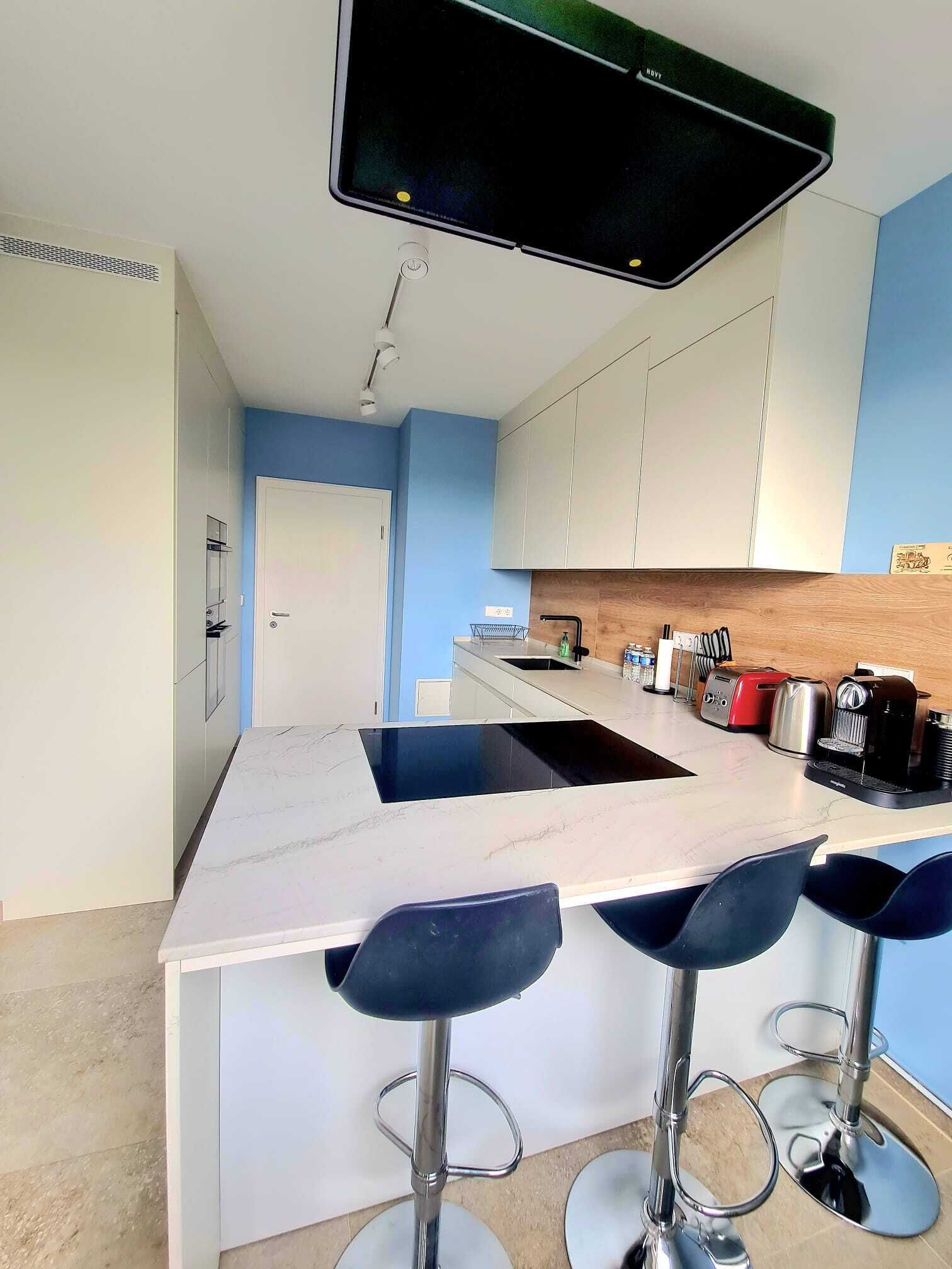 A modern kitchen with a central island, bar stools, and a built-in range hood.