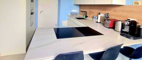 A modern kitchen with a central island, bar stools, and a built-in range hood.