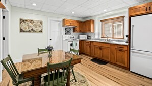 Una cocina moderna con armarios de madera, un refrigerador blanco, un microondas y una mesa de comedor con sillas.