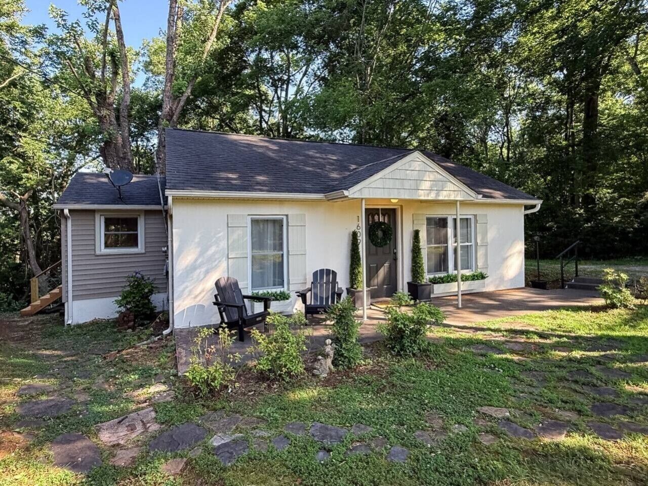 A single-story house with a front porch, two windows, and a door with a wreath.