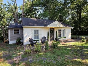 A single-story house with a front porch, two windows, and a door with a wreath.