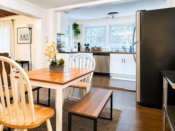 Eine moderne Küche mit weißen Schränken, einem Edelstahlkühlschrank und einem Essbereich mit Holztisch und Stühlen.