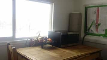 A room with a wooden table, a microwave, and a window with a view.