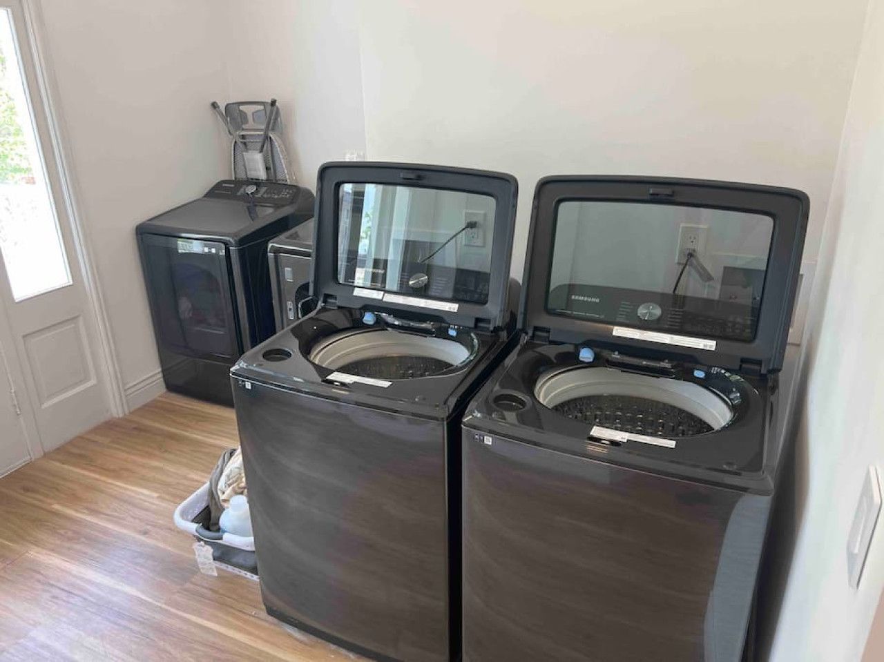A laundry room with two front-loading washing machines and a dryer.