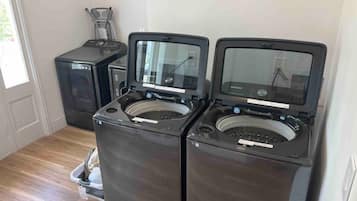 A laundry room with two front-loading washing machines and a dryer.