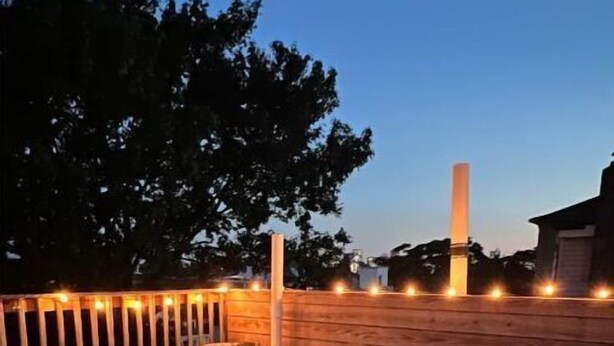 A wooden deck with a table and chairs, string lights, and a potted plant. - Entire One Bedroom Condo with Private Roofdeck (Boston)