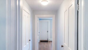 A narrow hallway with white doors and wooden flooring. - Simple Modern Elegance with Hudson Valley Mountains backdrop, 3rd Fl (Newburgh)
