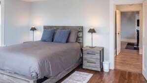 A bedroom with a bed, two bedside tables, and a nightstand. - Simple Modern Elegance with Hudson Valley Mountains backdrop, 3rd Fl (Newburgh)