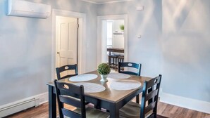 A dining room with a wooden table, four chairs, and a small potted plant. - Simple Modern Elegance with Hudson Valley Mountains backdrop, 3rd Fl (Newburgh)