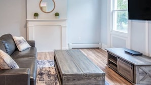 A living room with a fireplace, a television, and a coffee table. - Modern Modest Design  Newburgh, Beacon, Westpoint  2nd. FL Apt. (Newburgh)