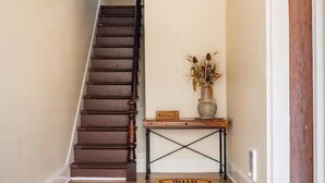 Un escalier en bois avec un paillasson sur lequel est écrit « BONJOUR » au bas.