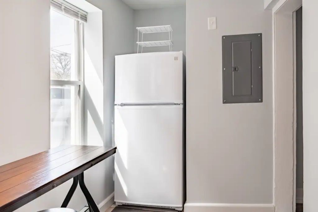 A small kitchen with a white refrigerator, a wooden table, and a window.