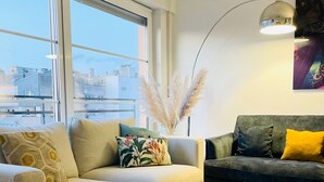 Una sala moderna con dos sofás, una mesa de centro de cristal y una lámpara de pie.