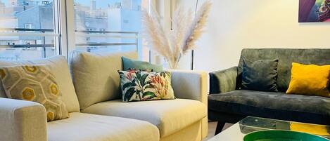 A modern living room with two sofas, a glass coffee table, and a floor lamp.