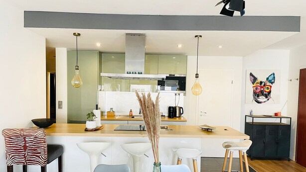 Una cocina moderna con una isla central, taburetes de bar e iluminación colgante.