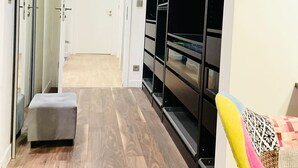 Un pasillo con un banco, un perchero y una puerta que da a otra habitación.