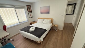 A bedroom with a bed, bedside tables, a desk, and a chair.