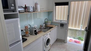 A compact kitchen with a microwave, toaster, and washing machine.