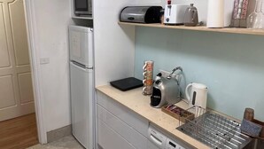 A compact kitchen with a microwave, toaster, kettle, and a coffee machine on the countertop.