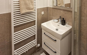 A bathroom with a white sink, a mirror, and a towel rack. - Ferienwohnung im Walserhaus (Altenmarkt-Zauchensee)