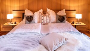 A neatly made bed with a striped bedspread, multiple pillows, and two bedside tables with lamps.