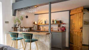 A modern kitchen with a marble island, bar stools, and a variety of kitchen appliances. - The Waterfall Retreat (Penrith)