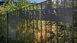 A metal gate with the words "THE WATERFRONT RETREAT" engraved on it. - The Waterfall Retreat (Penrith)
