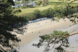 A beach with colorful beach huts and people enjoying the sand. - Ty Cerrig (Pwllheli)