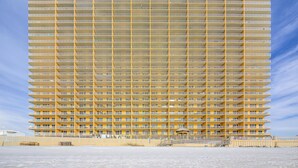 A high-rise hotel with multiple balconies, a central courtyard, and a beach view.