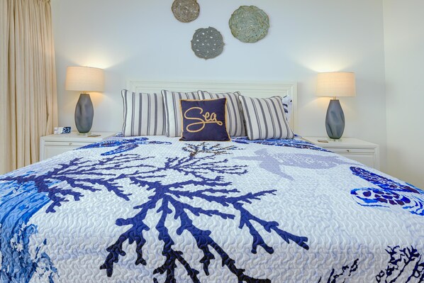 A bedroom with a large bed, two bedside tables, a headboard, and decorative wall art.