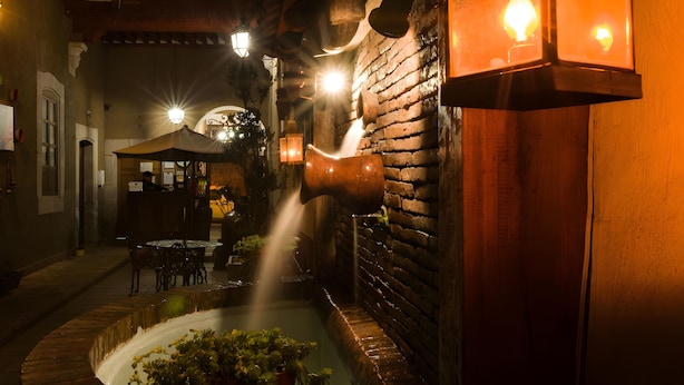 An outdoor patio area with a brick wall, a water feature, and ambient lighting. - Hotel del callejón Morelia (Morelia)