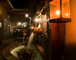 An outdoor patio area with a brick wall, a water feature, and ambient lighting. - Hotel del callejón Morelia (Morelia)