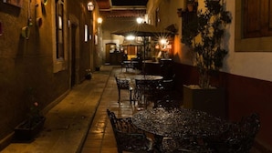 A narrow alley with tables and chairs, suggesting a dining area. There are potted plants and a building with a window in the background. - Hotel del callejón Morelia (Morelia)