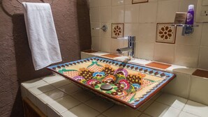 A bathroom with a colorful mosaic sink, a white towel hanging on a hook, and a shower area with a tiled wall. - Hotel del callejón Morelia (Morelia)