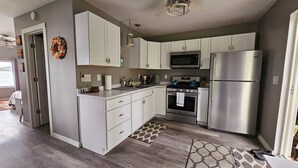A modern kitchen with white cabinets, stainless steel appliances, and a patterned rug. - Super spacious cabin. Simple layout and great views overlooking the lake! (Faribault)