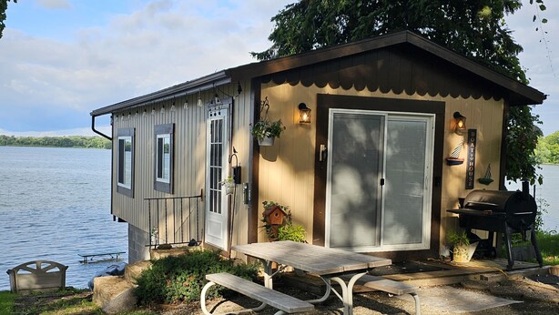 A small cabin with a picnic table and grill area, overlooking a lake. - Super spacious cabin. Simple layout and great views overlooking the lake! (Faribault)