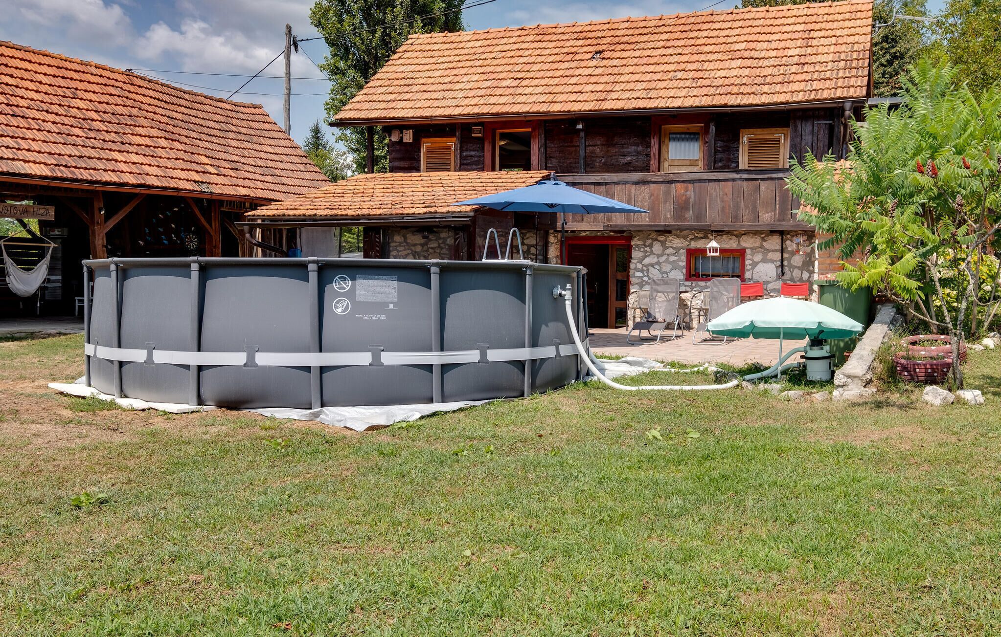 A house with a stone facade, a wooden deck, and a large above-ground pool.