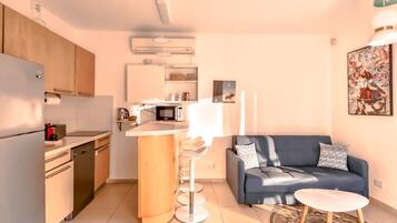 Un espacio habitable pequeño con kitchenette, un sofá y un comedor.