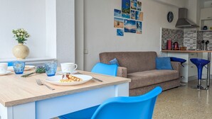 Et moderne køkken med spiseplads, der indeholder et træbord, blå stole og en beige sofa.