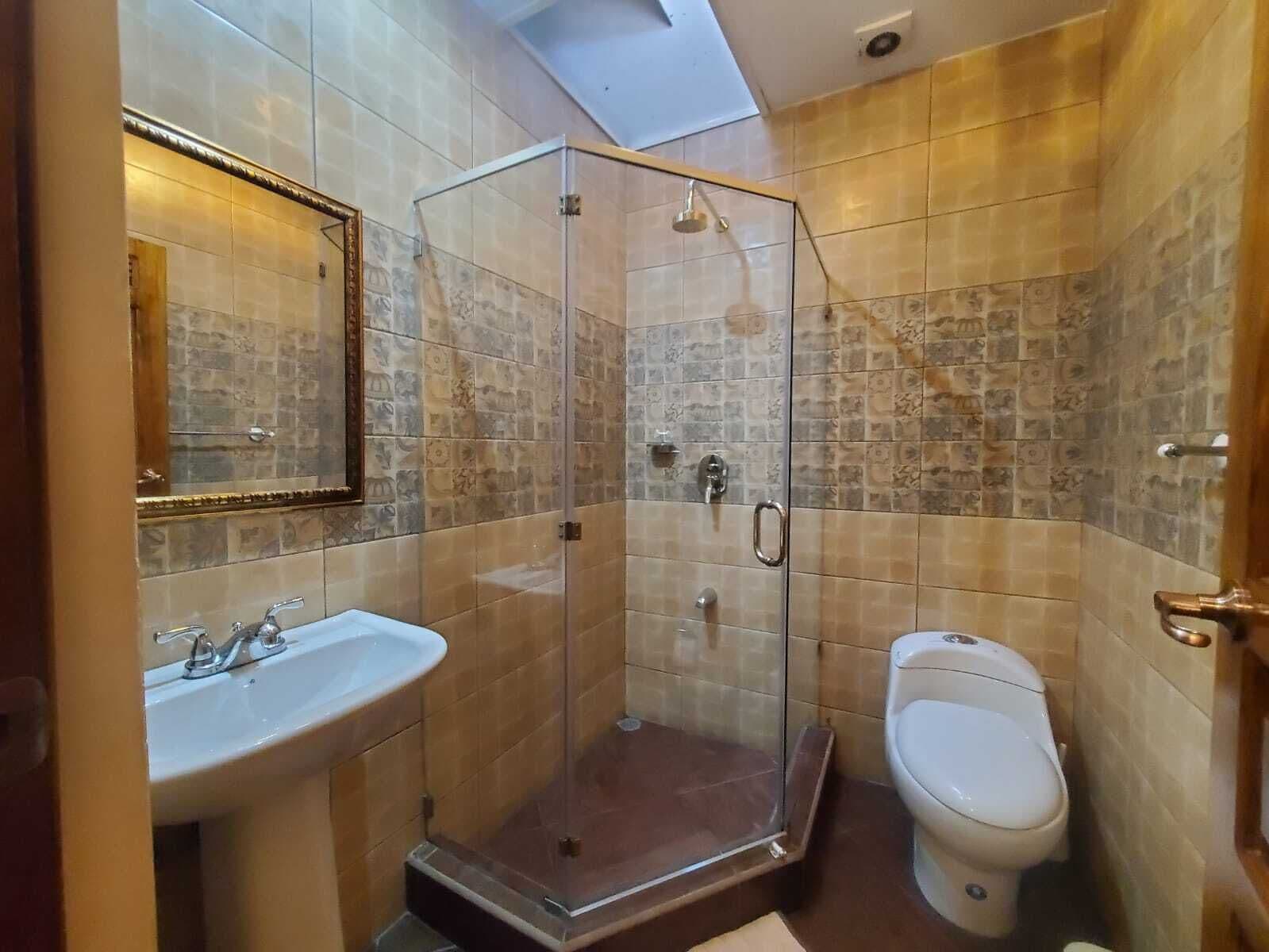 A bathroom with a glass-enclosed shower, a sink, and a toilet.