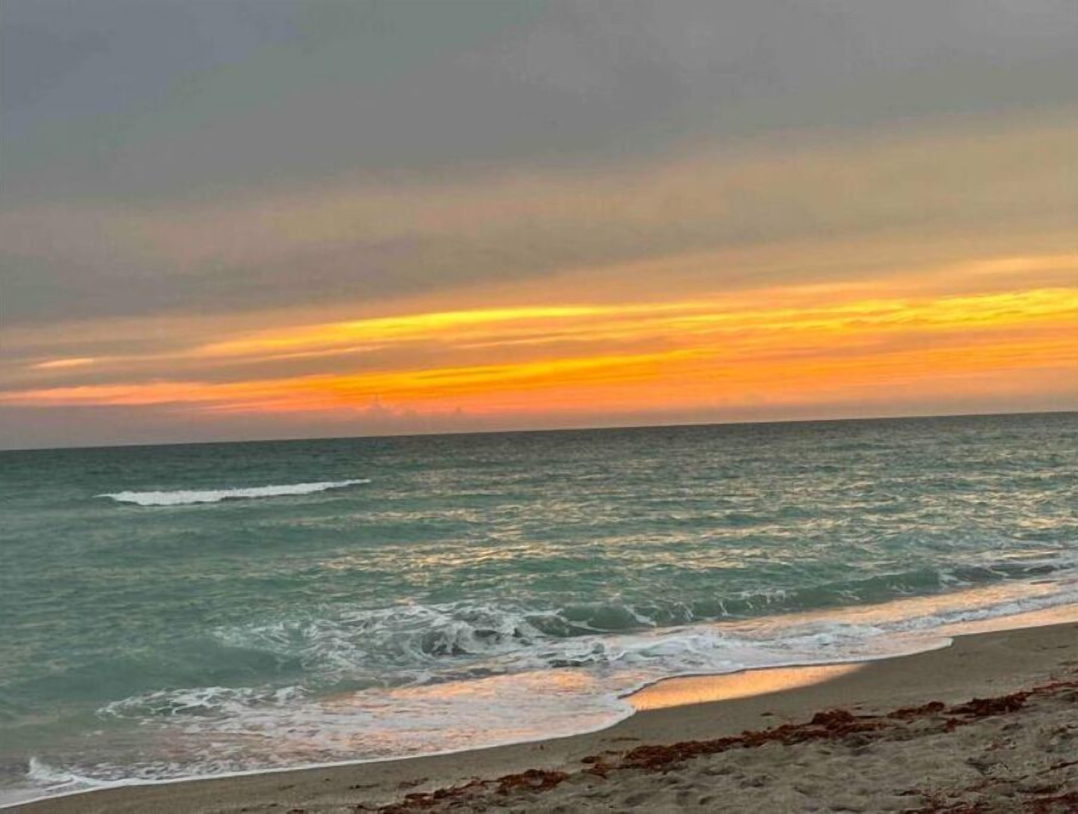 Ein Strand mit Wellen und einem Sonnenuntergang.