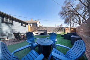 Ein Garten mit Terrasse, Sitzgelegenheiten und einem Grill.