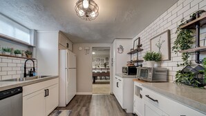 A modern kitchen with white cabinetry, a wooden floor, and a built-in microwave.