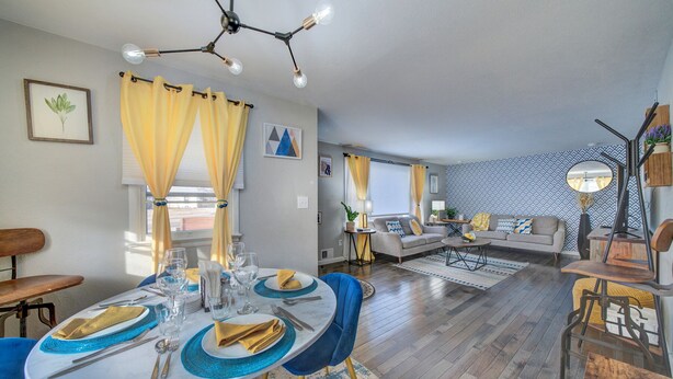 A dining area with a round table set for four, a sofa, and a patterned wall in a modern living space.