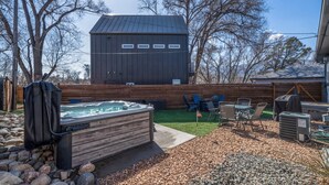 A backyard with a hot tub, outdoor seating, and a wooden deck.