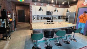 A modern kitchen with a central island, bar stools, and a coffee machine.