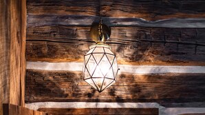 A wooden hallway with a geometric hanging light fixture and a table lamp. - Uncle Tom's 3BDR Cabin For Nature Lover (Grayling)