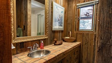 Un baño rústico de madera con un espejo grande, un lavabo y una ventana con vista al agua.